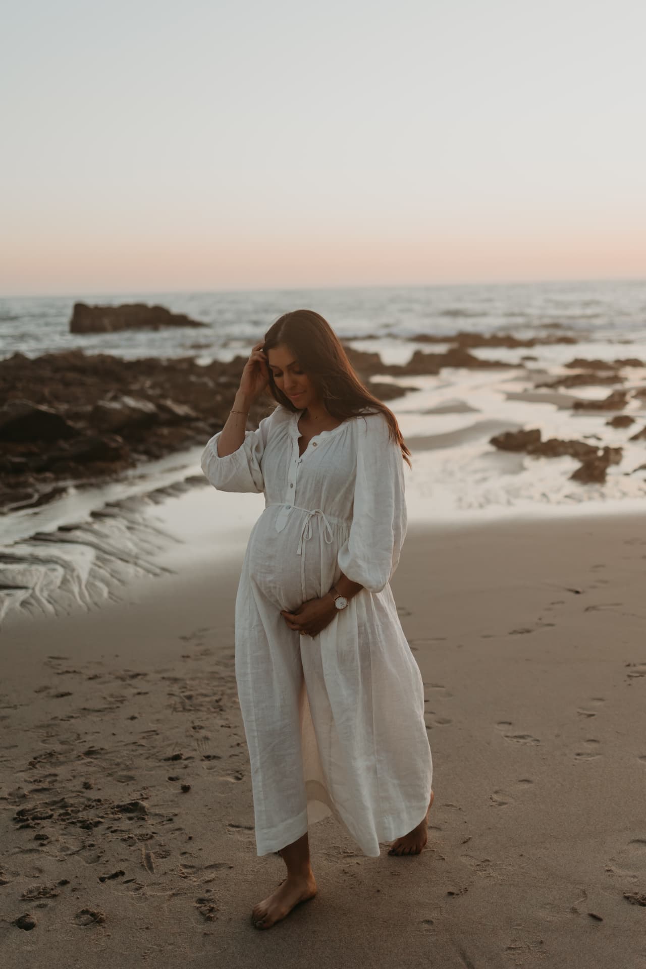 Stefani, schwanger am Strand im Sonnenuntergang, die Hände auf dem Bauch